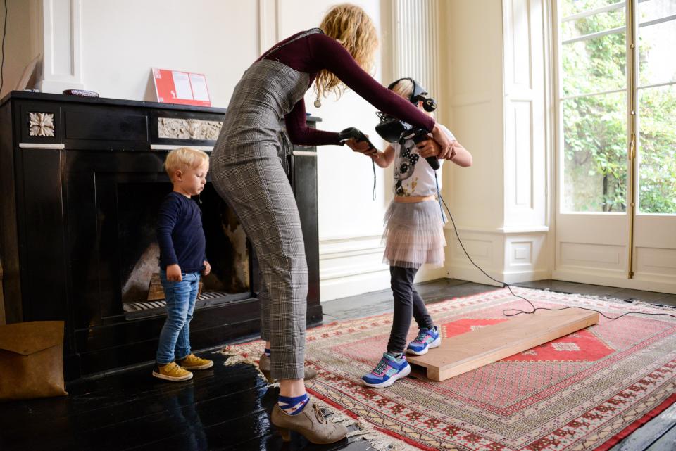 Vrouw helpt kind met VR-bril van plank